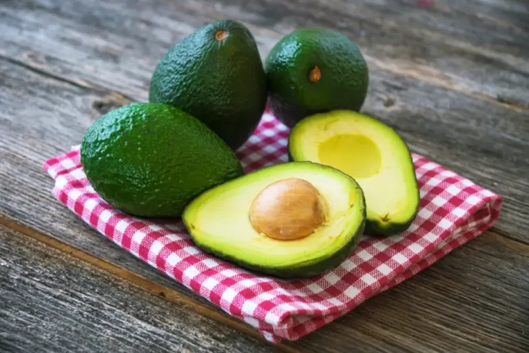 אבוקדו שלמים וחצויים מונחים על מגבת ושולחן