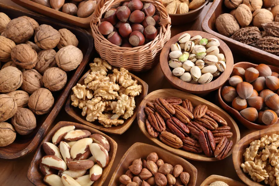 אגוזים טריים מסוגים שונים מונחים בקעריות עץ על שולחן