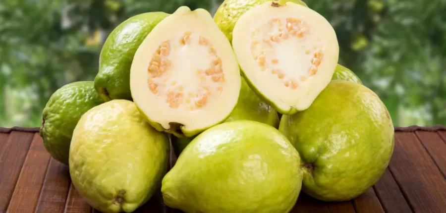 גויאבות שלמות וחצויות על שולחן עץ, עשירות בוויטמין C – לערכים תזונתיים