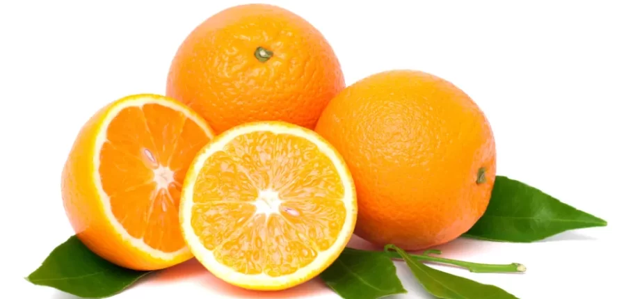 תפוזים שלמים וחצויים מונחים על עלים ירוקים עם רקע לבן